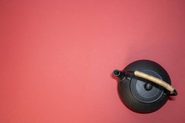 black metal tea kettle with handle, asian teapot on red background, copy space, place for text, tea ceremony, chinese new year 