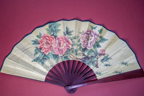 asian style handheld fan with flower print on red background, chinese new year theme, copy space