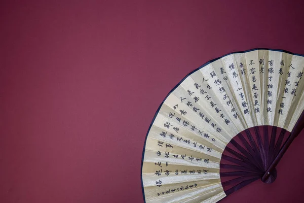 asian style handheld fan with hieroglyphs print on red background, chinese new year theme, copy space