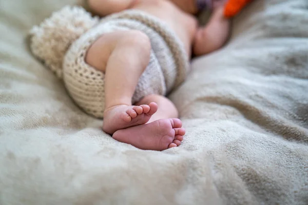 close up of tiny little baby feet on the sofa, infant pediatrician, child legs in knitted cloth diaper