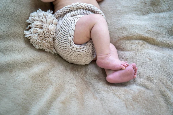 close up of tiny little baby feet on the sofa, infant pediatrician, child legs in knitted cloth diaper