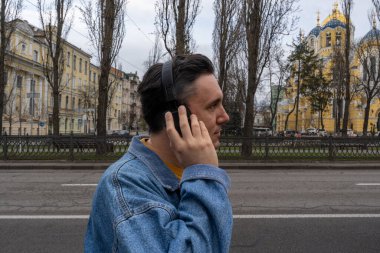 Mavi kot ceketli yakışıklı siyah saçlı adam boş sokakta duruyor. Kişi kablosuz kulaklıkla müzik dinliyor. Yalnızlık 
