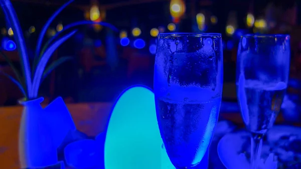 Blue light style, cocktails in the bar, two glasses of champagne on the table