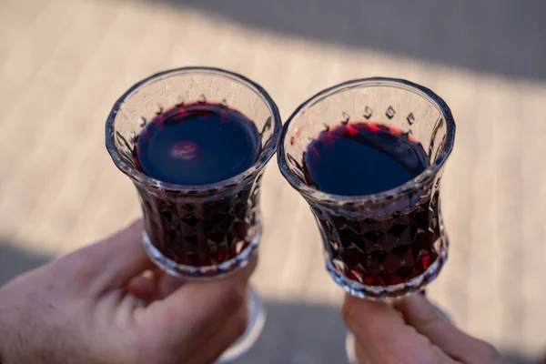 close up of man and woman hands holding two glasses of red wine on the street
