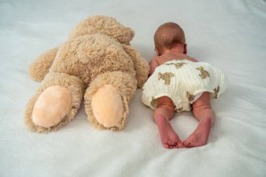 Yeni doğmuş şirin bebek peluş oyuncak ayıyla oynuyor. Çocukluktan beri en iyi arkadaşlar. Arkadaşlık. Çocuk öğrenme ve büyüme