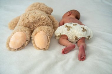Yeni doğmuş şirin bebek peluş oyuncak ayıyla oynuyor. Çocukluktan beri en iyi arkadaşlar. Arkadaşlık. Çocuk öğrenme ve büyüme