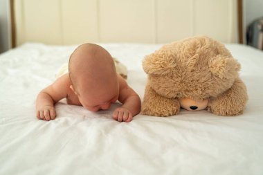 Yeni doğmuş şirin bebek peluş oyuncak ayıyla oynuyor. Çocukluktan beri en iyi arkadaşlar. Arkadaşlık. Çocuk öğrenme ve büyüme