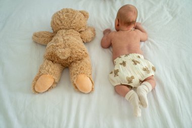 Yeni doğmuş şirin bebek peluş oyuncak ayıyla oynuyor. Çocukluktan beri en iyi arkadaşlar. Arkadaşlık. Çocuk öğrenme ve büyüme