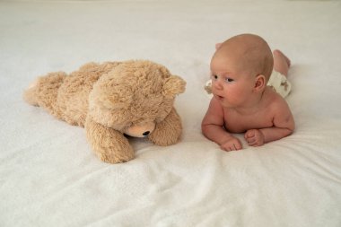 Yeni doğmuş şirin bebek peluş oyuncak ayıyla oynuyor. Çocukluktan beri en iyi arkadaşlar. Arkadaşlık. Çocuk öğrenme ve büyüme