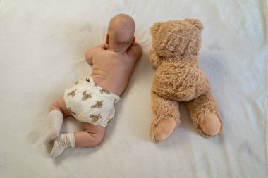 Yeni doğmuş şirin bebek peluş oyuncak ayıyla oynuyor. Çocukluktan beri en iyi arkadaşlar. Arkadaşlık. Çocuk öğrenme ve büyüme