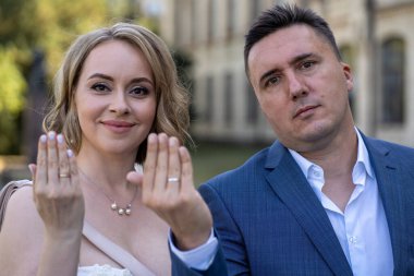 Bir karı koca evlilik yüzükleriyle ellerini gösteriyorlar. Yeni evli ve mutlu bir çiftin portresi. Evlilik yüzüğü parmağında. 