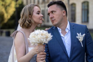 Parktaki gelin ve damadın portresi. Düğün günü. Gelin ve damat aşık. Genç ve mutlu bir çift yeni evli fotoşoplar için dışarıda poz veriyor. 