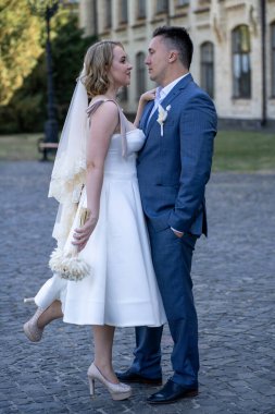 Düğün günü. Gelin ve damat el ele tutuşuyor. Yeni evli çiftimiz fotoşopesyon için dışarıda poz veriyor. Tüm vücut 