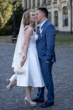 Düğün günü. Gelin ve damat el ele tutuşuyor. Yeni evli çiftimiz fotoşopesyon için dışarıda poz veriyor. Tüm vücut 