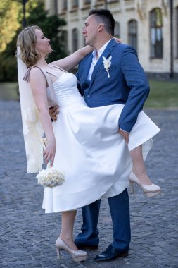 Düğün günü. Gelin ve damat el ele tutuşuyor. Yeni evli çiftimiz fotoşopesyon için dışarıda poz veriyor. Tüm vücut 