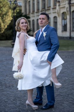 Düğün günü. Gelin ve damat el ele tutuşuyor. Yeni evli çiftimiz fotoşopesyon için dışarıda poz veriyor. Tüm vücut 