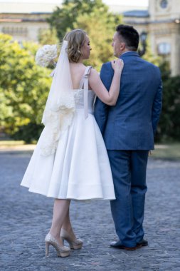 Düğün günü. Gelin ve damat el ele tutuşuyor. Yeni evli çiftimiz fotoşopesyon için dışarıda poz veriyor. Tüm vücut 