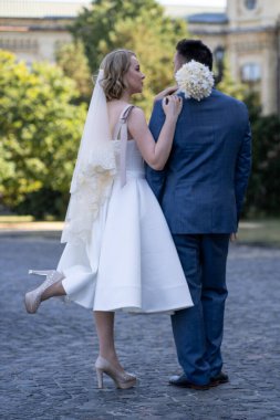 Düğün günü. Gelin ve damat el ele tutuşuyor. Yeni evli çiftimiz fotoşopesyon için dışarıda poz veriyor. Tüm vücut 