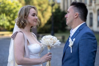 Parktaki gelin ve damadın portresi. Düğün günü. Gelin ve damat aşık. Genç ve mutlu bir çift yeni evli fotoşoplar için dışarıda poz veriyor. 