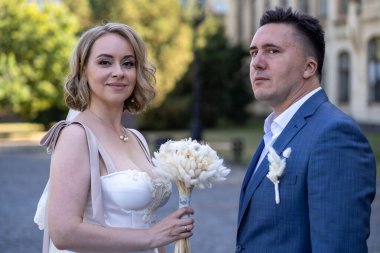 Parktaki gelin ve damadın portresi. Düğün günü. Gelin ve damat aşık. Genç ve mutlu bir çift yeni evli fotoşoplar için dışarıda poz veriyor. 