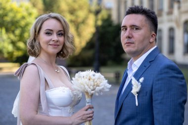 Parktaki gelin ve damadın portresi. Düğün günü. Gelin ve damat aşık. Genç ve mutlu bir çift yeni evli fotoşoplar için dışarıda poz veriyor. 