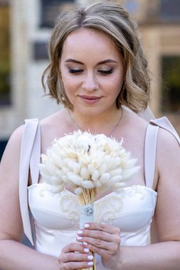 Beyaz gelinlik içinde elinde bir buket çiçekle güzel bir gelinin portresi. Düğün günü. Açık havada gelin fotosferi
