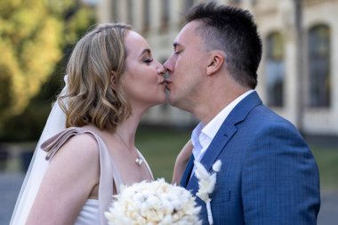 Düğün günü. Gelin ve damat sokakta öpüşüyor. Yeni evlendim ve yeni bir aile kurdum. Düğün portresi 