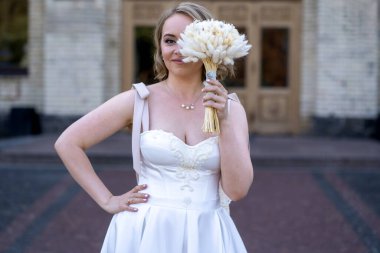 Beyaz gelinlik içinde elinde bir buket çiçekle güzel bir gelinin portresi. Düğün günü. Açık havada gelin fotosferi