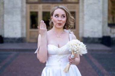 Beyaz gelinlik içinde elinde bir buket çiçekle güzel bir gelinin portresi. Düğün günü. Açık havada gelin fotosferi