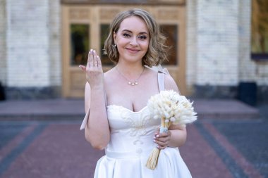 Beyaz gelinlik içinde elinde bir buket çiçekle güzel bir gelinin portresi. Düğün günü. Açık havada gelin fotosferi