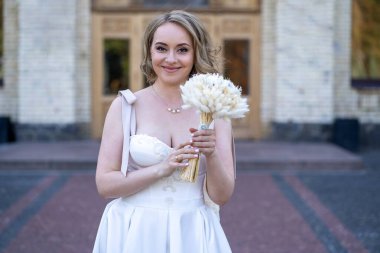 Beyaz gelinlik içinde elinde bir buket çiçekle güzel bir gelinin portresi. Düğün günü. Açık havada gelin fotosferi