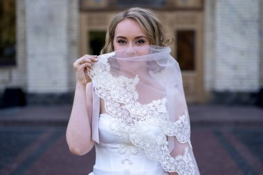 Beyaz gelinlik içinde elinde bir buket çiçekle güzel bir gelinin portresi. Düğün günü. Açık havada gelin fotosferi