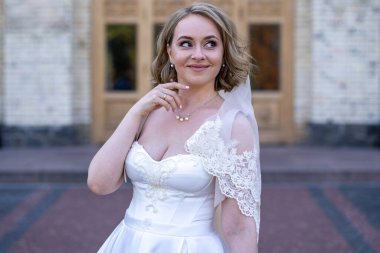 Beyaz gelinlik içinde elinde bir buket çiçekle güzel bir gelinin portresi. Düğün günü. Açık havada gelin fotosferi