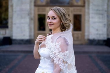 Beyaz gelinlik içinde elinde bir buket çiçekle güzel bir gelinin portresi. Düğün günü. Açık havada gelin fotosferi