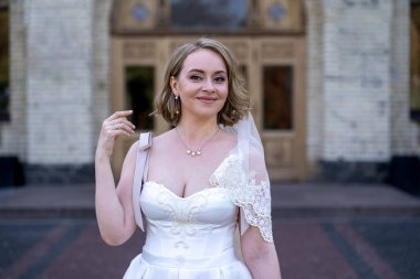 Beyaz gelinlik içinde elinde bir buket çiçekle güzel bir gelinin portresi. Düğün günü. Açık havada gelin fotosferi