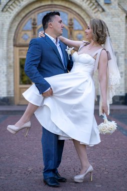 Düğün günü. Gelin ve damat el ele tutuşuyor. Genç ve mutlu bir çift yeni evli fotoşoplar için dışarıda poz veriyor. 