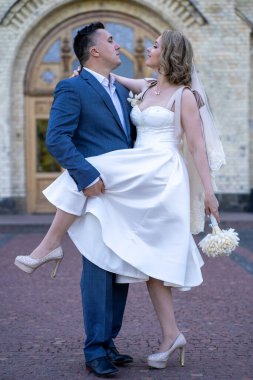 Düğün günü. Gelin ve damat el ele tutuşuyor. Genç ve mutlu bir çift yeni evli fotoşoplar için dışarıda poz veriyor. 