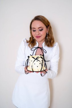 Beyaz kısa elbiseli güzel bir doğum günü kızı Bento Pastası Lambeth 'i ellerinde tutuyor. Doğum günü kutlamanız kutlu olsun. Makyajlı kadın pastaya bakar. 