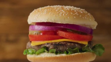 Kameranın önünde dönen taze malzemelerle lezzetli sulu bir burger. Şefin masasında servis edilen ızgara biftekli leziz hamburger. Yakın çekim.