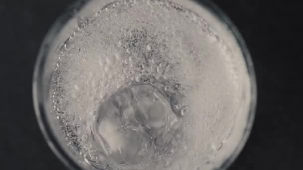 小さなガラスの中の氷のキューブのクローズアップ 透明なガラスの中の氷 透明なガラスの中の水 輝く水の氷のキューブの空気の泡は 水の空気の泡のガラスが浮かぶまで上昇します アイスドリンクアイスキューブ — ストック動画