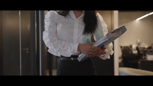 一位富有创意 时尚的女商人手里拿着一叠文件走在走廊上 不同的种族 不同的人 创造性的团队 商业伙伴 — 图库视频影像