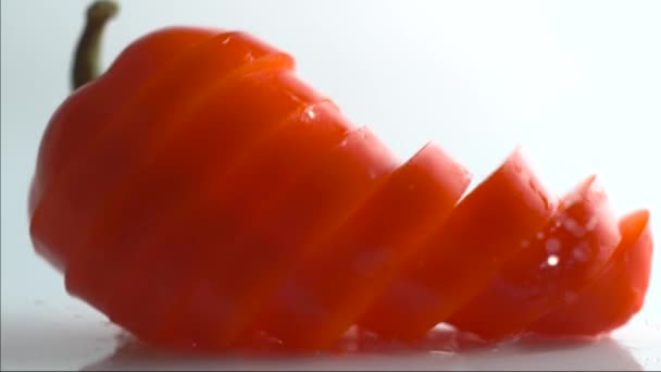 一片白色背景上的红辣椒环以慢动作落下 成熟的胡椒片落在白色的背景上 — 图库视频影像