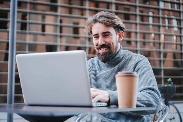 stock image Smiling young businessman using laptop to work remotely from coffee terrace, Portrait of successful freelancer or student working on new project. Business concept. High quality photo
