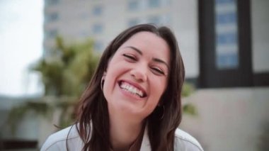 Dışarıda duran beyaz dişli, gülümseyen ve kameraya bakan genç bir kadının portresi. Olumlu davranışları olan mutlu genç bir kızın ön yüzü. Yüksek kalite 4k görüntü