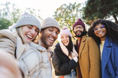 Group of young people smiling and having fun taking selfie portrait. Five multiracial happy friends looking at camera. Funny outdoor activity of cheerful students away from home. Lifetyle concept