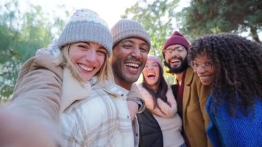 Group of young people smiling and having fun taking selfie portrait. Five multiracial happy friends looking at camera. Funny outdoor activity of cheerful students away from home. Lifetyle concept