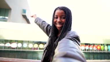 POV screen view of one african american young woman with braids smiling having a video call with a smartphone device. Front view of a happy girl taking a selfie portrait. High quality 4k footage