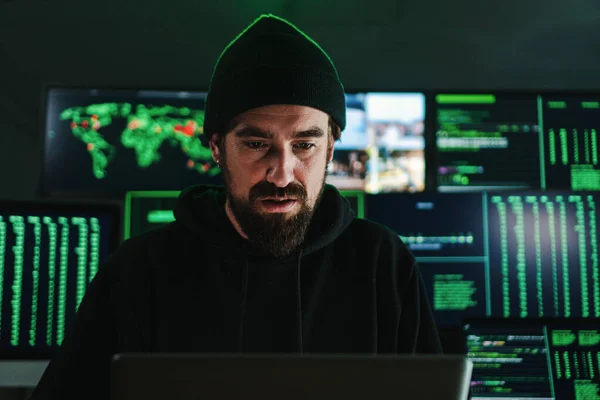 One criminal hacker man programming a phishing virus, at background a lot of data screens. One caucasian developer working on internet firewall system. Cyber security concept. High quality photo