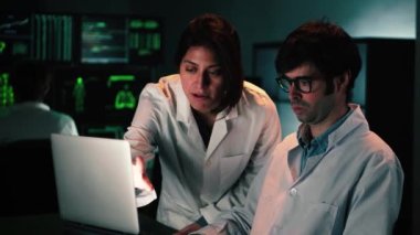Two concentrated medical scientist with lab coat analyzing a pharmacy test with a laptop computer. A couple of a medicine doctors working in a biology investigation. Science concept. High quality