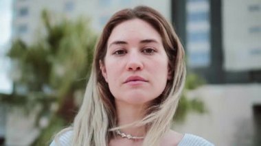 Close up portrait of blonde caucasian young woman looking serious at camera. Pretty teenage girl staring front with sad attitude. High quality 4k footage
